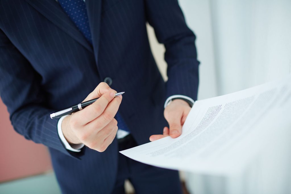 Documenti legali firmati su scrivania con edificio condominiale sullo sfondo a rappresentare la responsabilità civile dell’amministratore di condominio.